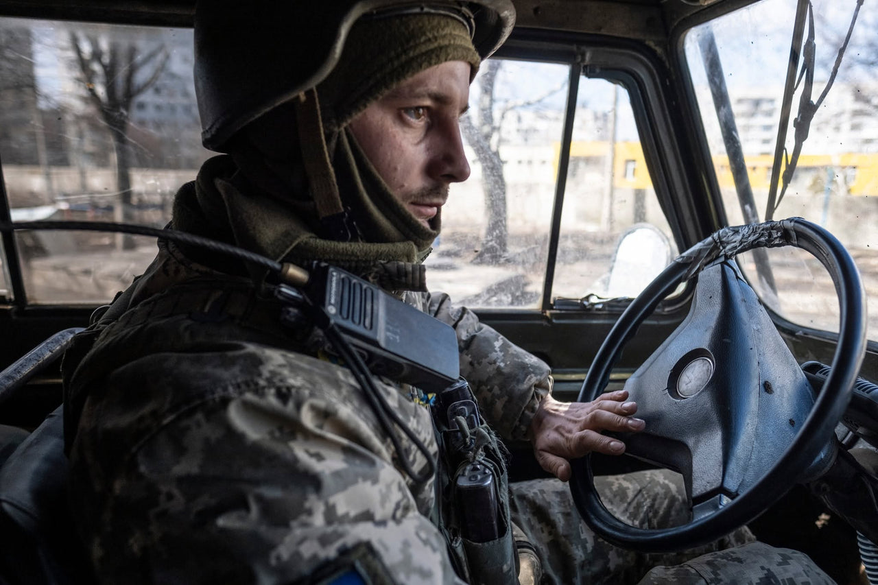 A servicemember at the wheel of a vehicle.