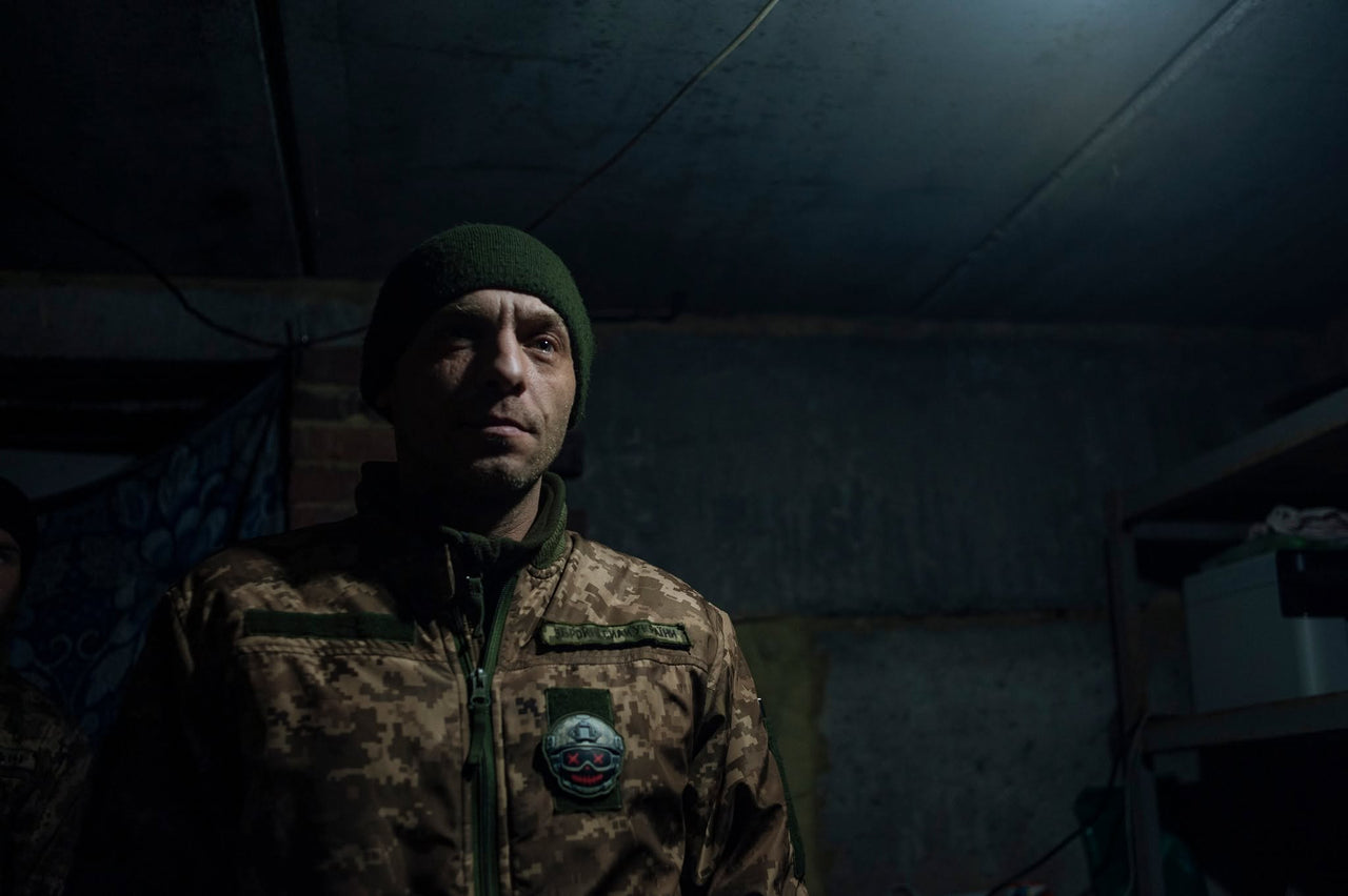 A servicemember in a dimly lit interior.