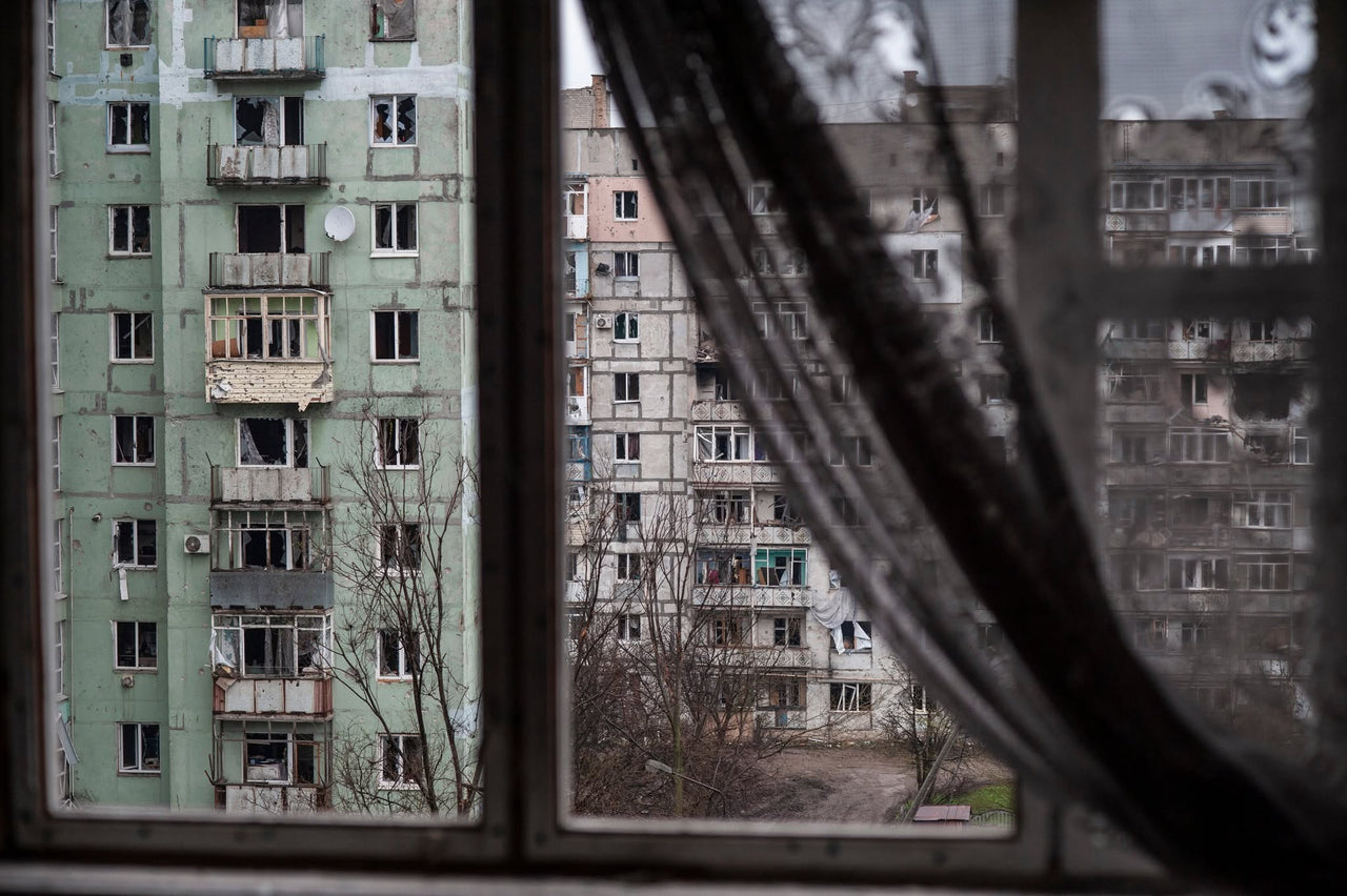 Damaged apartment buildings seen through a window.