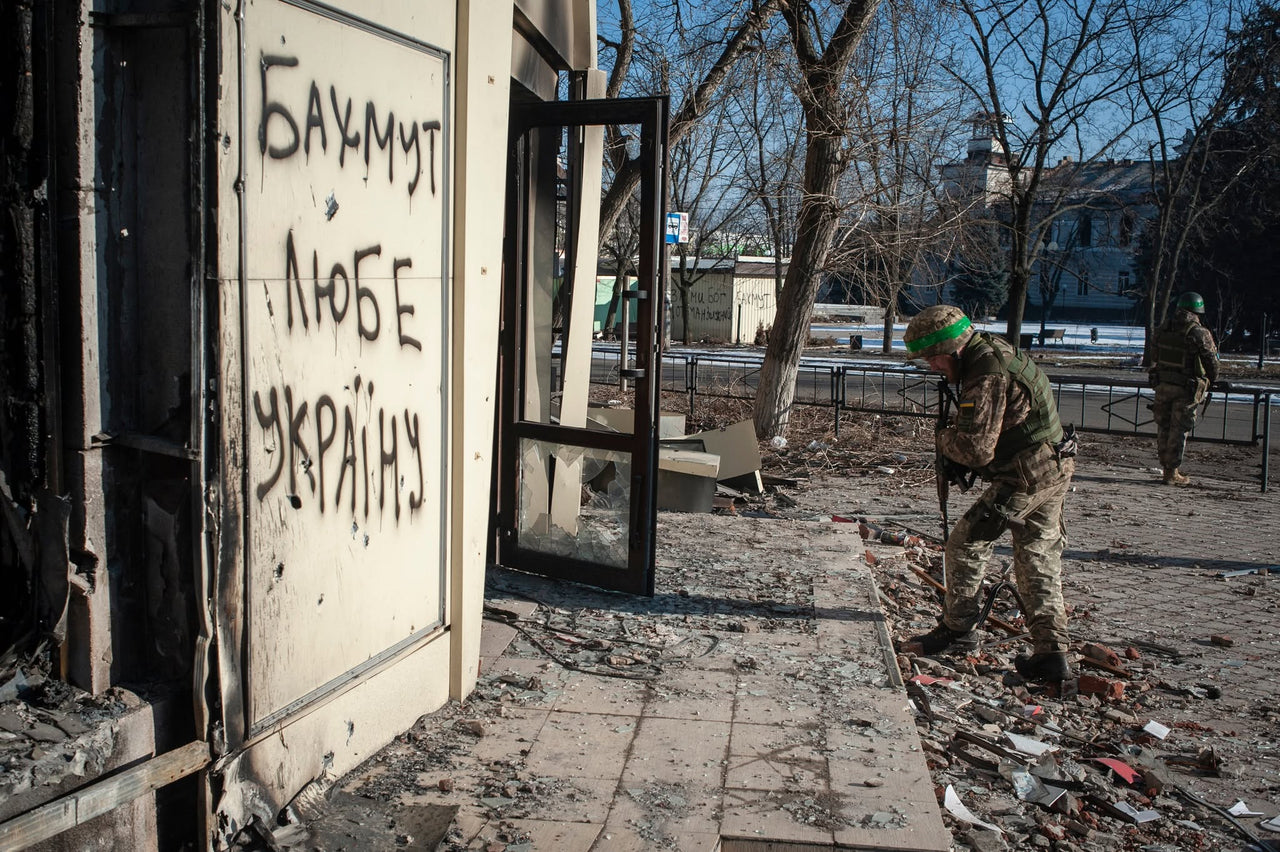 A defender beside a doorway bearing a message about Bakhmut and Ukraine.
