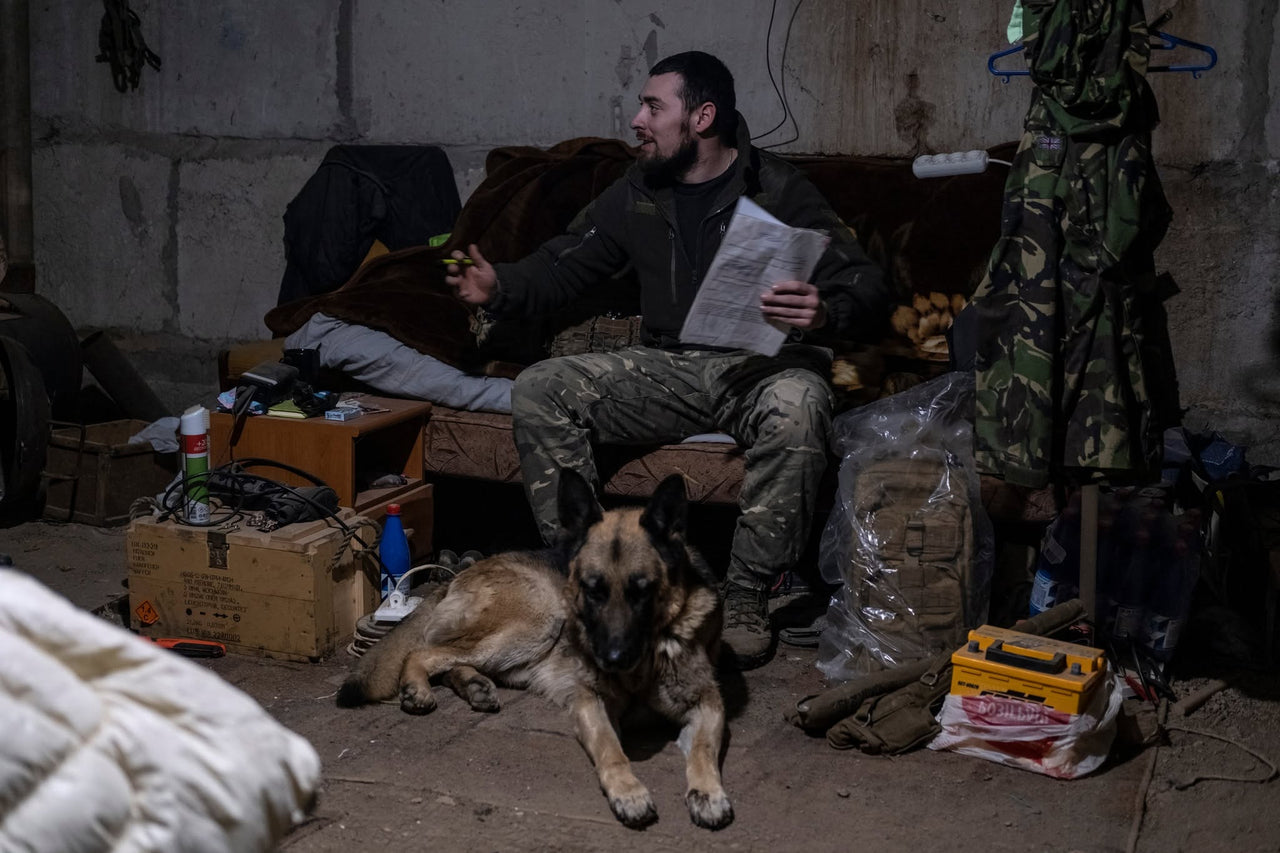 Servicemembers indoors with a dog.