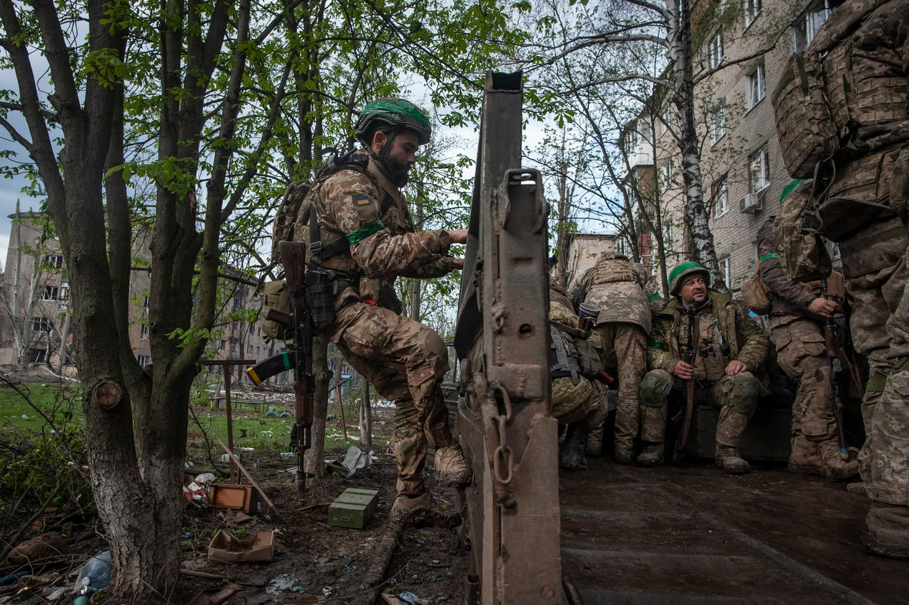Servicemembers beside a building among trees.